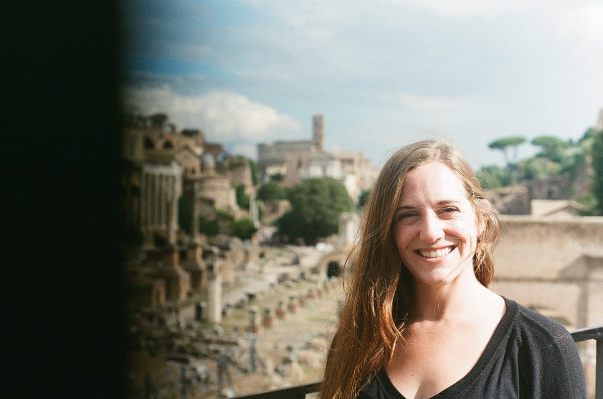 Carolyn smiling in front of ancient ruins on a trip.