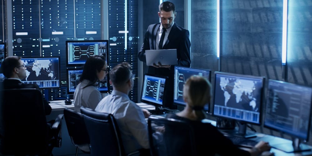 IT professionals working among monitors and server equipment.